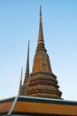 Three ornate temple spires against a blue sky. The spires are decorated with colorful tiles and gold accents, and are different