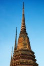 Three ornate temple spires against a blue sky. The spires are decorated with colorful tiles and gold accents, and are different