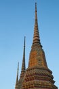 Three ornate temple spires against a blue sky. The spires are decorated with colorful tiles and gold accents, and are different