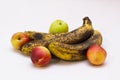 Three overripe bananas with yellow peel covered of brown spots and four ripe nectarines on light surface