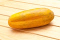 Three overripe yellow cucumbers on the background of old wooden boards. Autumn harvest. Vegetables and dry leaves, stems