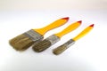 Three paint brushes with a width of 1 inch, 2 inches and 0.5 inches with yellow handles on a white background Royalty Free Stock Photo