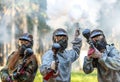 Three paintball players with guns and smoke grenade aiming Royalty Free Stock Photo