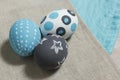 Three painted boiled eggs on a gray and turquoise napkin