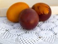 Three painted Easter eggs lie on a hand-knitted napkin