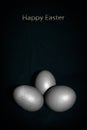 Three painted silver eggs on a dark green background. Royalty Free Stock Photo