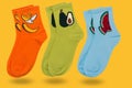 Three pairs of colored socks with drawings of fruits, levitating, casting a shadow, on a yellow background