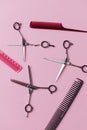 Three pairs of metal hairdresser scissors and plastic combs over pink
