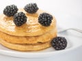 Three pancakes with blackberry on white