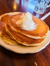 Three Pancakes with butter on a brown table