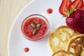 Three pancakes with cheese and strawberries and sauce on a white dish against wood background. Delicious cheese pancake and Royalty Free Stock Photo