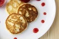 Three pancakes with cheese and strawberries and sauce on a white dish against wood background. Delicious cheese pancake and Royalty Free Stock Photo