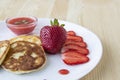 Three pancakes with cheese and strawberries and sauce on a white dish against wood background. Delicious cheese pancake and Royalty Free Stock Photo