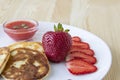 Three pancakes with cheese and strawberries and sauce on a white dish against wood background. Delicious cheese pancake and Royalty Free Stock Photo