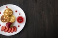 Three pancakes with cheese and strawberries and sauce on a white dish against wood background. Delicious cheese pancake and Royalty Free Stock Photo