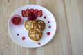 Three pancakes with cheese and strawberries and sauce on a white dish against wood background. Delicious cheese pancake and Royalty Free Stock Photo