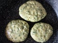 Three pancakes with spinach cooking on frying pan