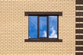 A three-pane window against a new brick wall. A fragment of a house wall for a construction-themed design. Clouds are reflected in Royalty Free Stock Photo