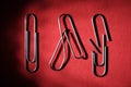 Three paper clips on a red background, whole, bent and broken. The concept of breaking the bonds Royalty Free Stock Photo