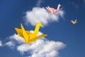 Three paper cranes flying above clouds. Royalty Free Stock Photo