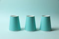 Three paper cups on light blue background. Thimblerig game Royalty Free Stock Photo