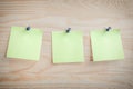 Three paper notes pinned to wooden bulletin board. Mockup green paper note pad attached with push pin on wood background Royalty Free Stock Photo