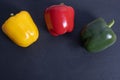 Three paprika on a black stone tile