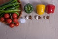 Three paprika, different vegetables and spices lie on a table and a wooden tray