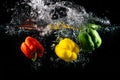 Three paprika`s falling in the water isolated on black background Royalty Free Stock Photo