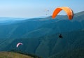 Three paragliders fly over a mountain valley in summer sunny day in the Carpathians in Ukraine. Royalty Free Stock Photo