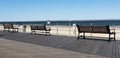 Three park benches on a boardwalk by the beach Royalty Free Stock Photo