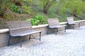 three park benches brown with wood lining high wall bushes granite pavement