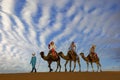 Three Riders And Their Handler Travel Through The Saharan Desert On Their Camels In Morocco Royalty Free Stock Photo