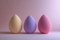 Three pastel beauty blending sponges arranged on a soft pink surface with gentle light Royalty Free Stock Photo