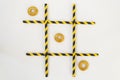 Three pastry bagels lie in a row in the game of tic-tac-toe, in a grid on a white background. The grid consists of colored tubes