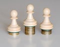 Three pawns chess pieces on columns of coins, symbolizing the distribution of first, second and third places by income