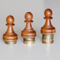 Three pawns chess pieces on columns of coins, symbolizing substantial income inequality