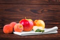 Three peaches and a few apples on a white tablecloth and on a wooden background. Tasty, juicy and ripe fruits. Royalty Free Stock Photo