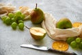 Three pears with green grapes and dried pieces of orange decorated with silver vintage knife and brown cloth on gray background