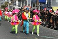 Three people in carnival costumes marching along a street