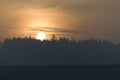 Three people and a dog walk a dam wall under a hazy autumn sunset Royalty Free Stock Photo