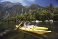 Three People Kayaking In Mountain Lake