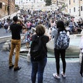 Three people are photographing with the phone in Piazza di Spagna in Rome