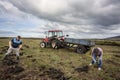 Three people threw turf sods into a trailer.