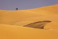 Three people on top of dunes in Desert Sahara with beautiful lines and colors at sunrise. Merzouga, Morocco