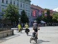 Three people tourists are enjoying their vacation, riding their bikes down a main street in