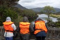 Three people waiting on a bridge wearing life jackets while they wait for a boat at the Meeting of the Waters, Ring of Kerry,