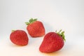 Three perfectly cleaned strawberries with leaves isolated on the white background
