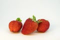 Three perfectly cleaned strawberries with leaves isolated on the white background