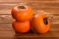 Three persimmons on wooden table Royalty Free Stock Photo